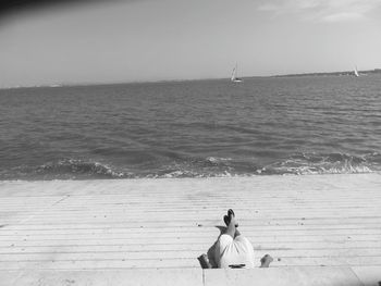 Couple sitting on beach against sky