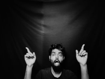 Portrait of young man wearing mask against black background