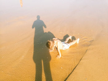 High angle view of shirtless boy practicing push-ups on shore at beach