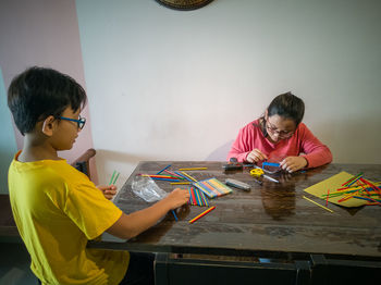 A young girl is constructing colorful plastic sticks with glue gun.  building geometric figures.