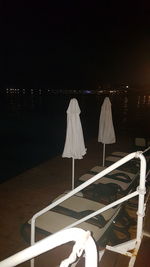 Chair on table at beach against sky at night