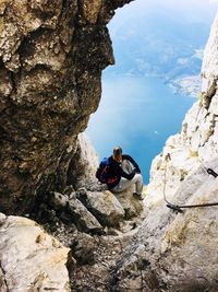 People on rocks by mountains against sky