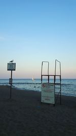 Information sign on beach against clear sky