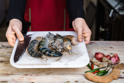 Midsection of man holding fish on cutting board