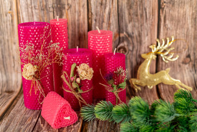 Handmade pink honey candles made of natural wax on a background of wooden boards.