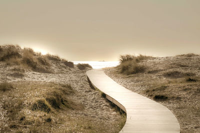 View of footpath leading towards sea against clear sky