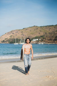 Full length portrait of shirtless man standing on beach