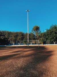 Street lights on field against clear blue sky