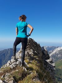 Full length of woman standing on rock against clear sky