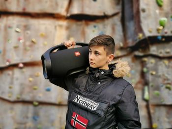 Man looking away while standing against wall