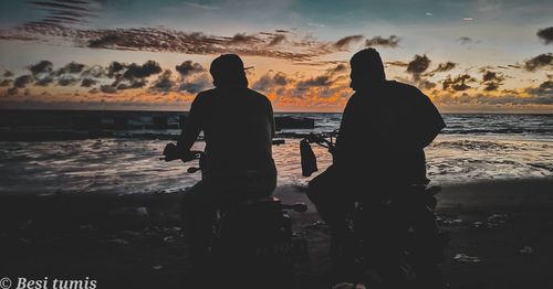 Silhouette people standing on beach against sky during sunset