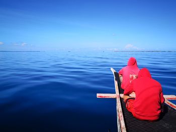 Rear view of man on sea against blue sky