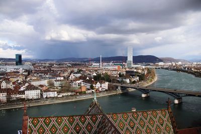 Bridge over river amidst buildings in city against sky