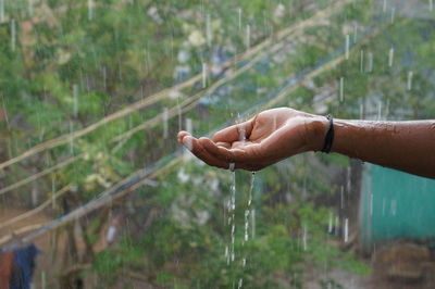 Water falling on cropped hand during rainy season