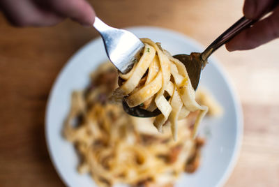 Close-up of hands holding pasta in fork