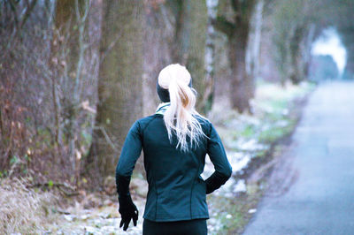 Rear view of woman jogging in forest during winter