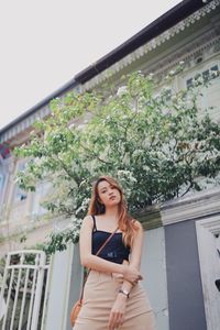 Portrait of woman standing against building
