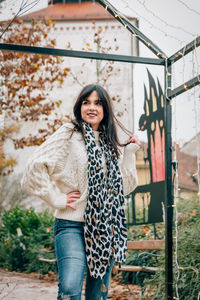 Portrait of smiling young woman standing against wall