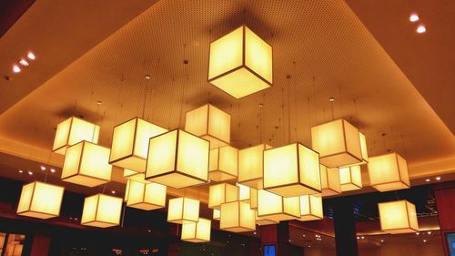 Low angle view of illuminated pendant lights hanging from ceiling