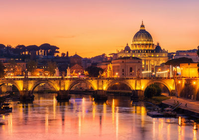 View of illuminated bridge over river during sunset