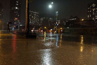 Wet illuminated city against sky at night