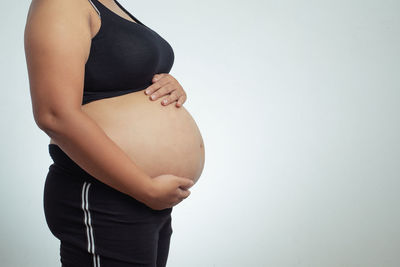 Midsection of woman touching face against gray background