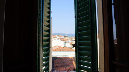 Buildings against sky seen through wodden window