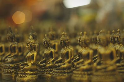 Close-up of golden buddha statues arranged in temple