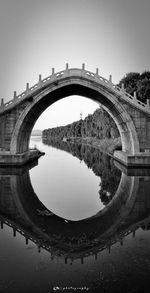 Arch bridge over river against sky