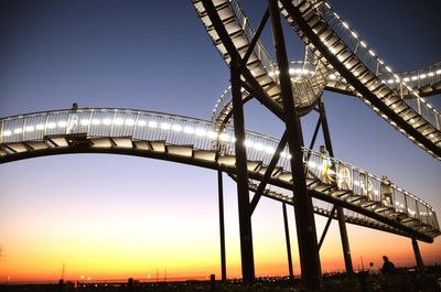 Low angle view of illuminated bridge against sky during sunset