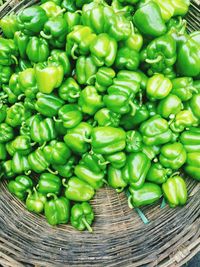 High angle view of green bell peppers in wicker basket for sale