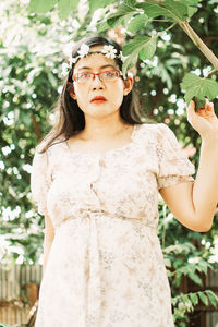 Portrait of a young woman standing against plants