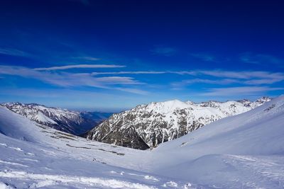 Scenic view of snowcapped mountains against blue sky