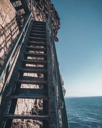 Staircase by sea against clear sky