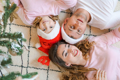 Family in santa hats with their daughter, in light, cozy clothes, lying