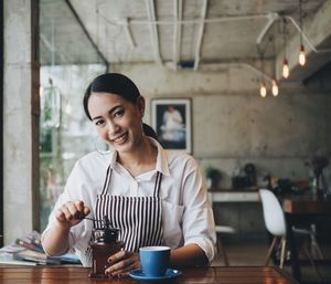 Portrait of young woman holding coffee cup in restaurant