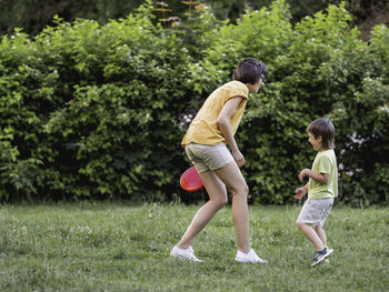 Mother and son play frisbee on grass lawn. summer vibes.  leisure activity. sports game at backyard.