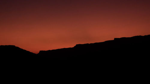 Silhouette mountains against orange sky