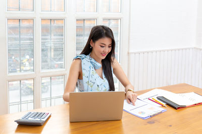 Young woman using phone on table