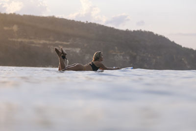 Female surfer in the ocean at sunset