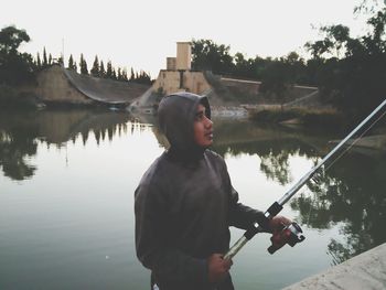 Boy fishing in lake against clear sky