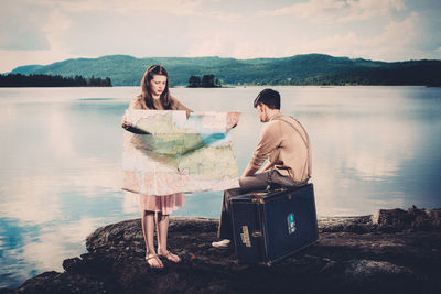 A  teenager pair standing by lake with a map