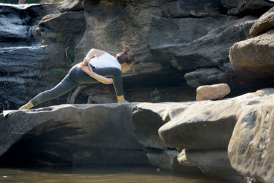 Rear view of mature woman exercising on rock formation