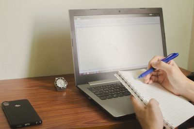 Midsection of person using mobile phone on table