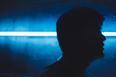 Close-up portrait of silhouette woman against blue wall