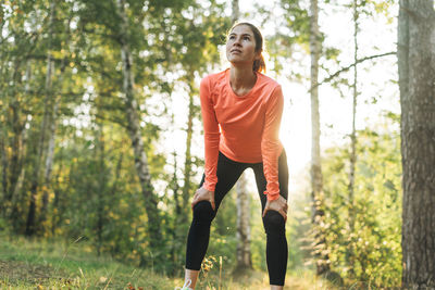 Young slim woman brunette in sport clothes running at the forest on golden hour sunrise 