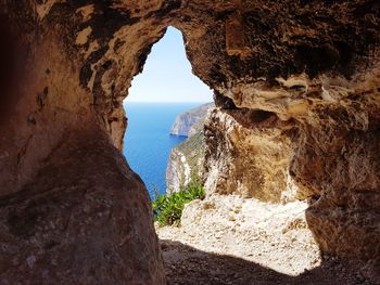 Scenic view of beach seen through cave