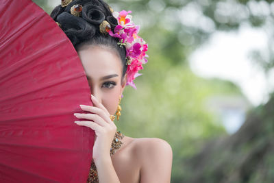 Portrait of young woman in traditional clothing holding umbrella while standing outdoors