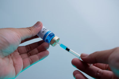 Cropped image of person holding hand against blue background