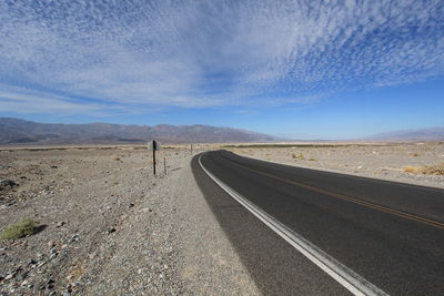 Road passing through mountains against cloudy sky